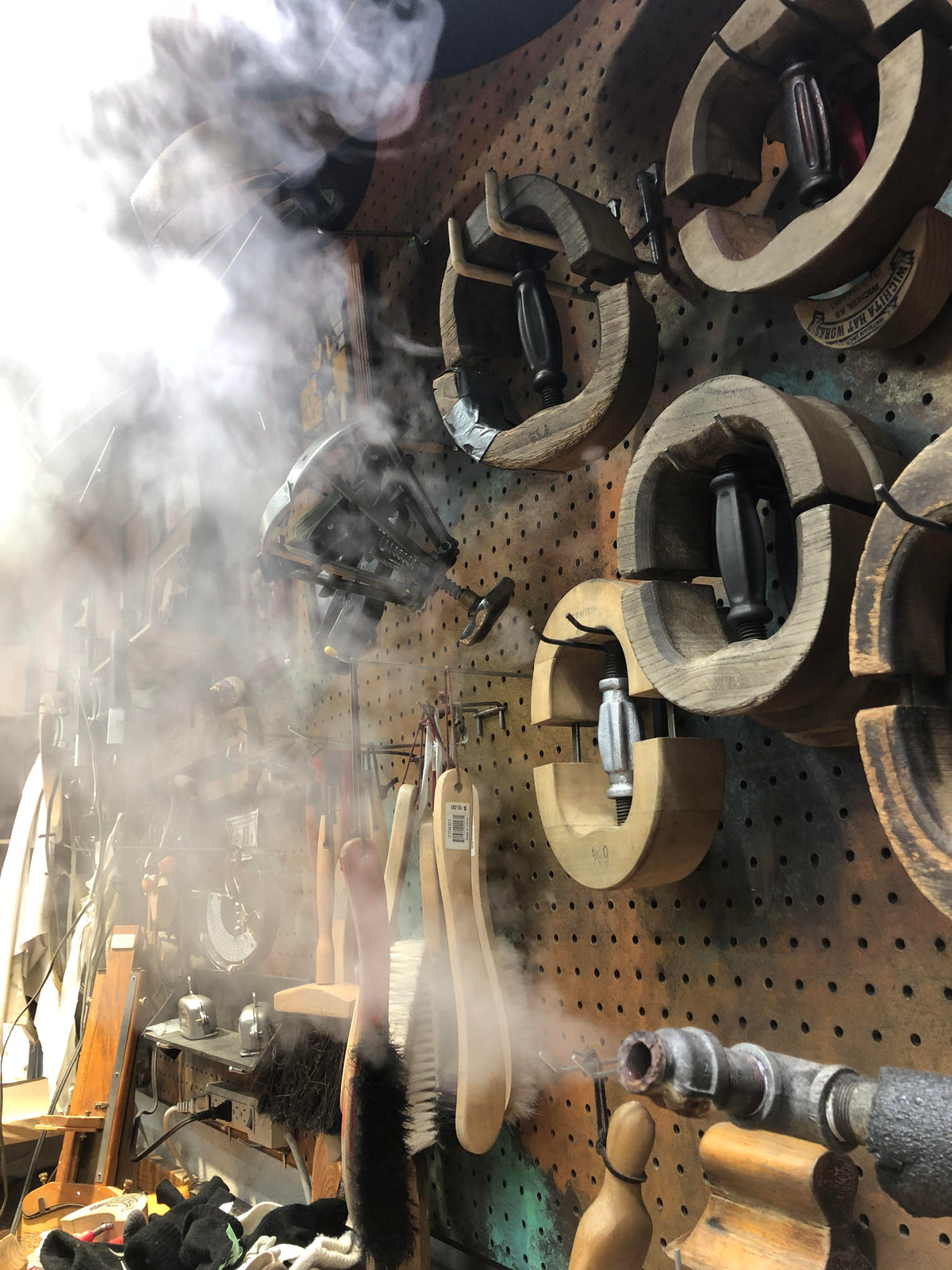 Hand-shaping a hat with steam over vintage wooden hat blocks at Hatman Jack's